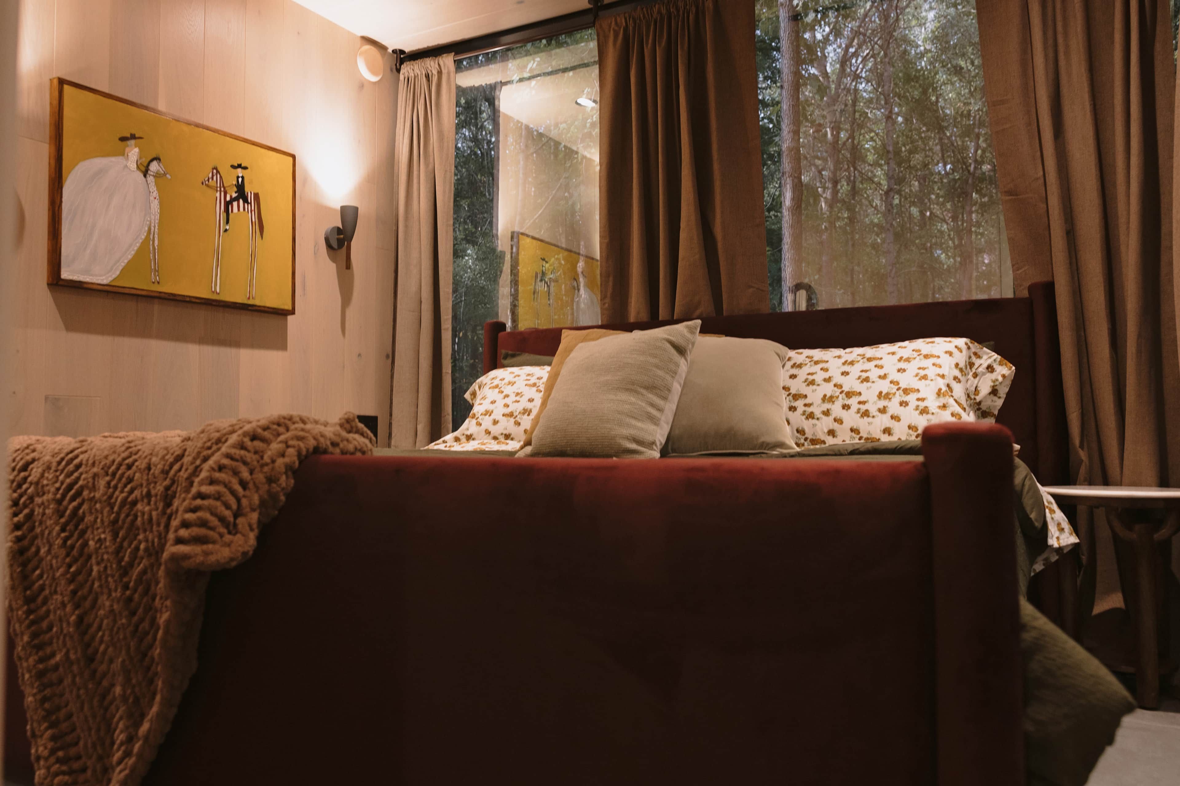 A bed with a red headboard, a blanket, and floral-patterned pillows.