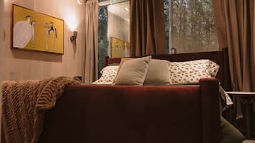 A bed with a red headboard, a blanket, and floral-patterned pillows.