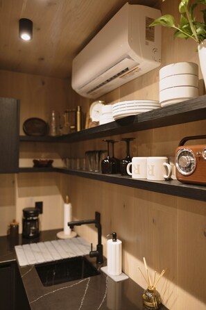 A kitchen with wooden shelves, a coffee machine, and a sink. - Glass House IV tucked in the East Texas forest (Gregg County)