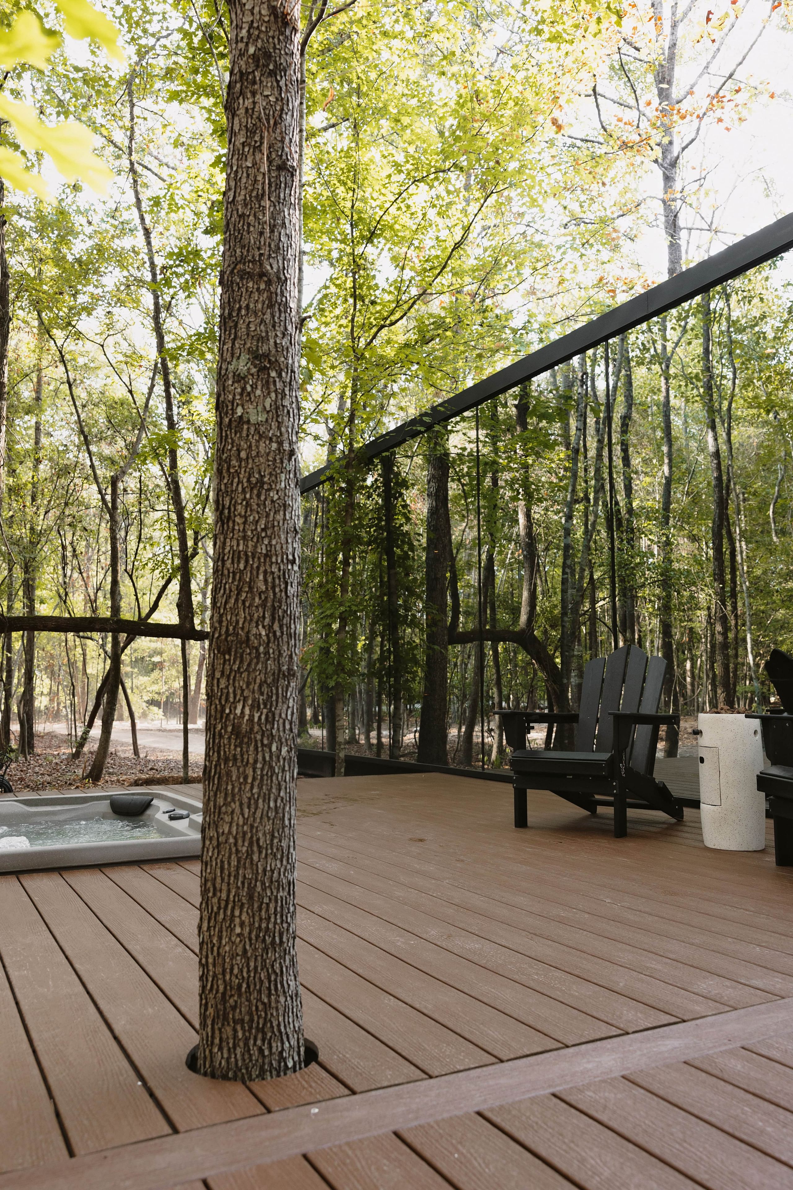 A wooden deck with a hot tub, a grill, and a seating area with chairs.