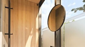 Ein modernes Badezimmer mit einem Holzbadezimmermöbel, einem runden Spiegel und einer Toilette.