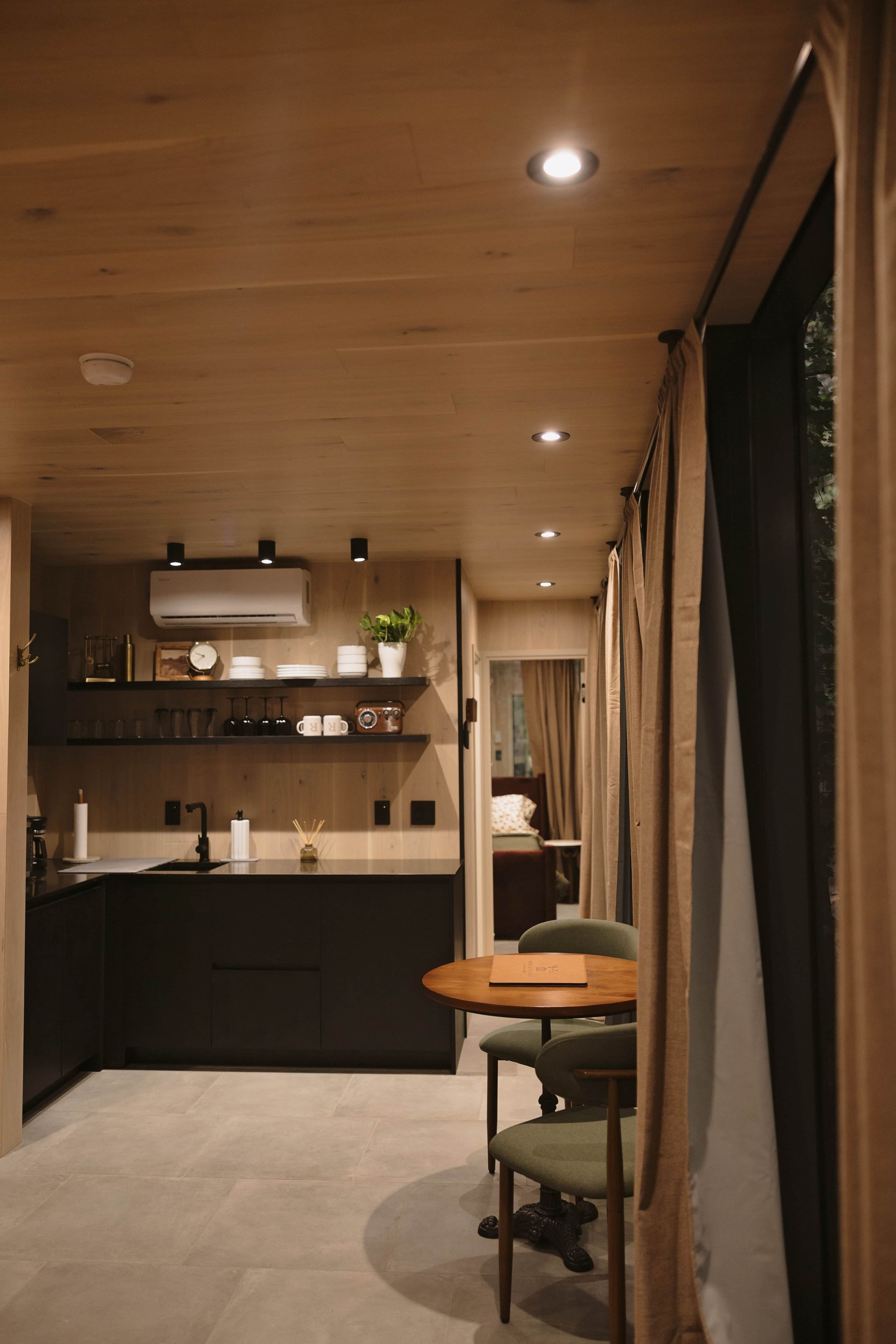 Une cuisine moderne avec des meubles en bois, un îlot central et un coin repas comprenant une table et des chaises.