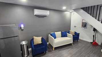 A modern kitchen with a built-in refrigerator, a grey wall with an air conditioning unit, and a staircase leading to a landing.