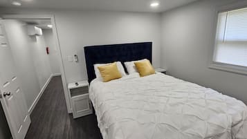 A bedroom with a bed, bedside tables, a wardrobe, and a window.