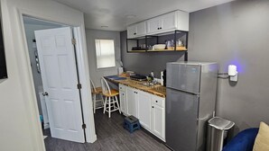 Une cuisine de taille réduite avec des meubles blancs, un réfrigérateur en acier inoxydable et un plan de travail en bois.