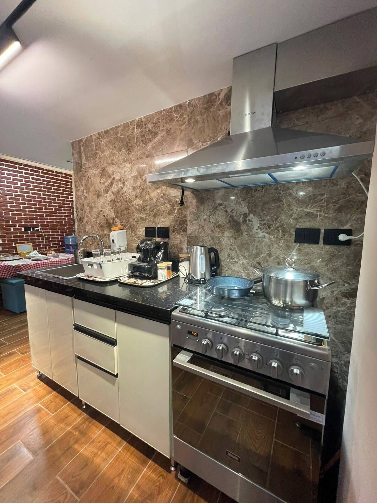 A modern kitchen with a stainless steel stove, a built-in oven, and a brick-patterned backsplash.