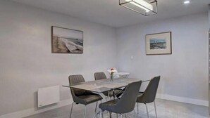 A dining area with a rectangular table, six chairs, and two framed pictures on the walls.