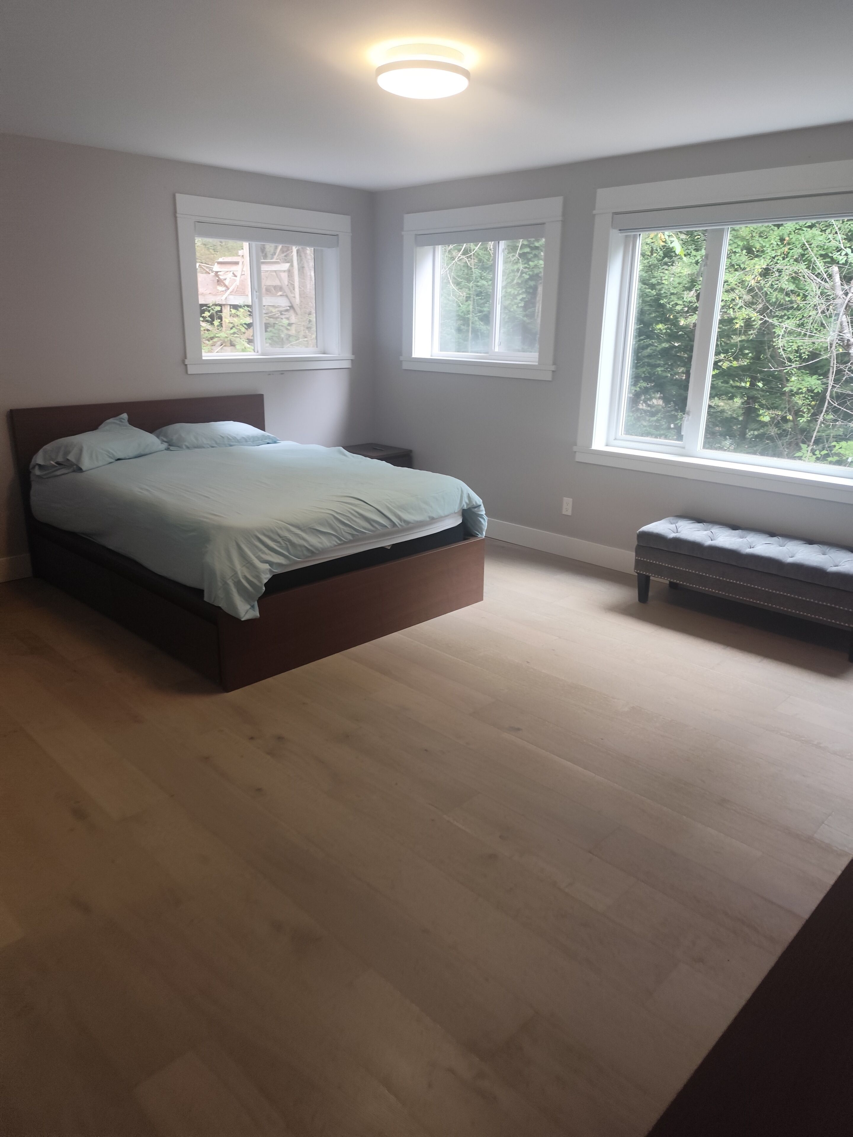 Une chambre à coucher avec un lit, un banc et de grandes fenêtres.