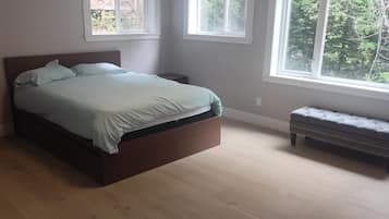 Une chambre à coucher avec un lit, un banc et de grandes fenêtres.