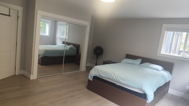 A bedroom with a bed, a bedside table, a mirror, and a ceiling light.