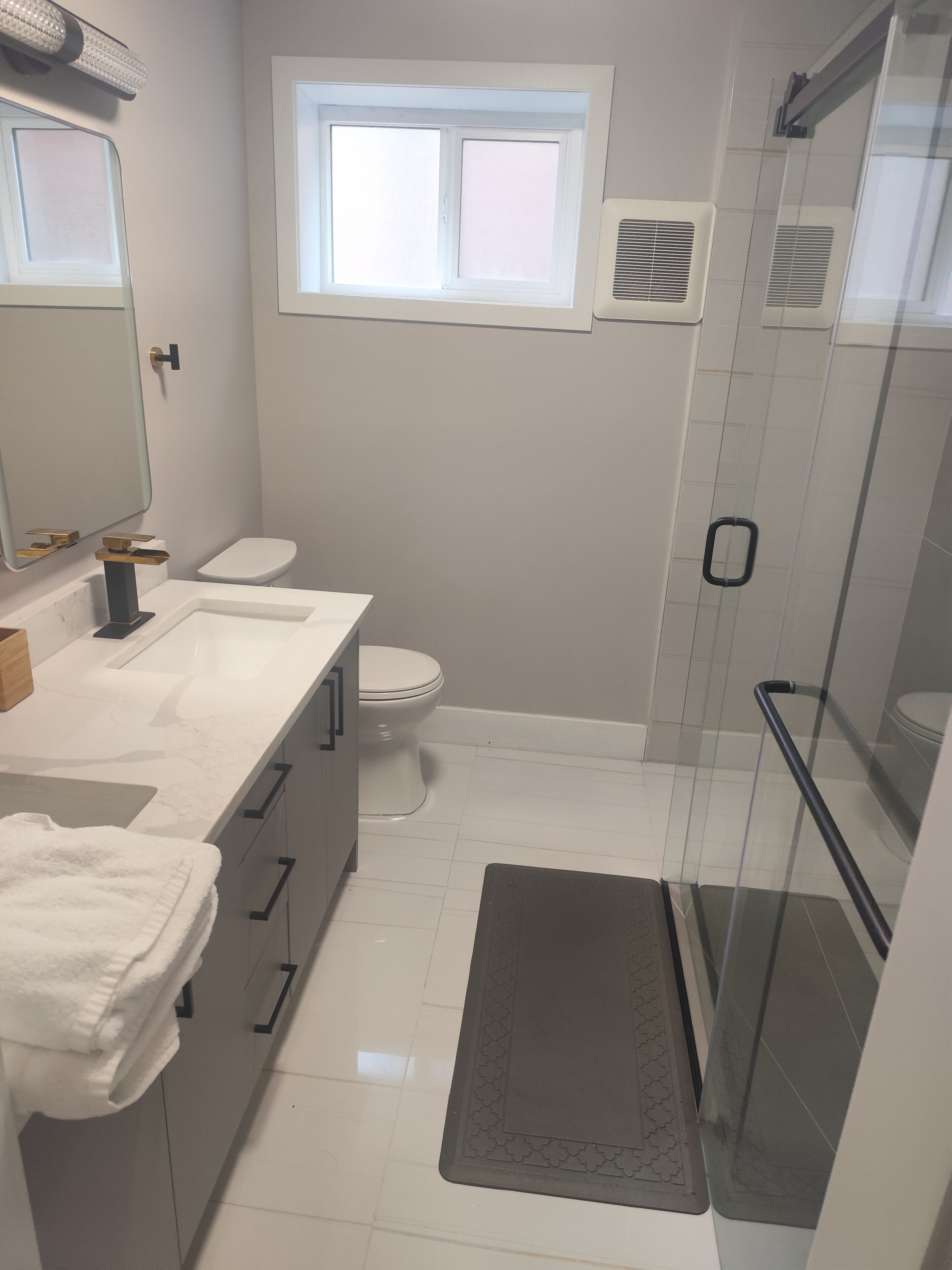 Une salle de bain avec un lavabo blanc, des toilettes et une cabine de douche en verre.