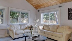 A living room with two beige sofas, a glass coffee table, and a vase with flowers.