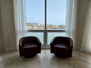 A room with two leather armchairs facing a large window with a view of a coastal area. - The Lighthouse, Unit 3A-Oyster Bay, St. Maarten. Walk to Beach (Oyster Bay)