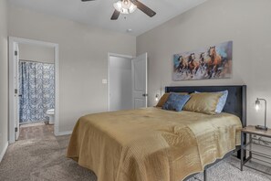 A bedroom with a large bed, a ceiling fan, a painting on the wall, and a nightstand with a lamp. - Telluride:5 BR/5 BA Home-2 Minutes from A&M Campus (College Station)