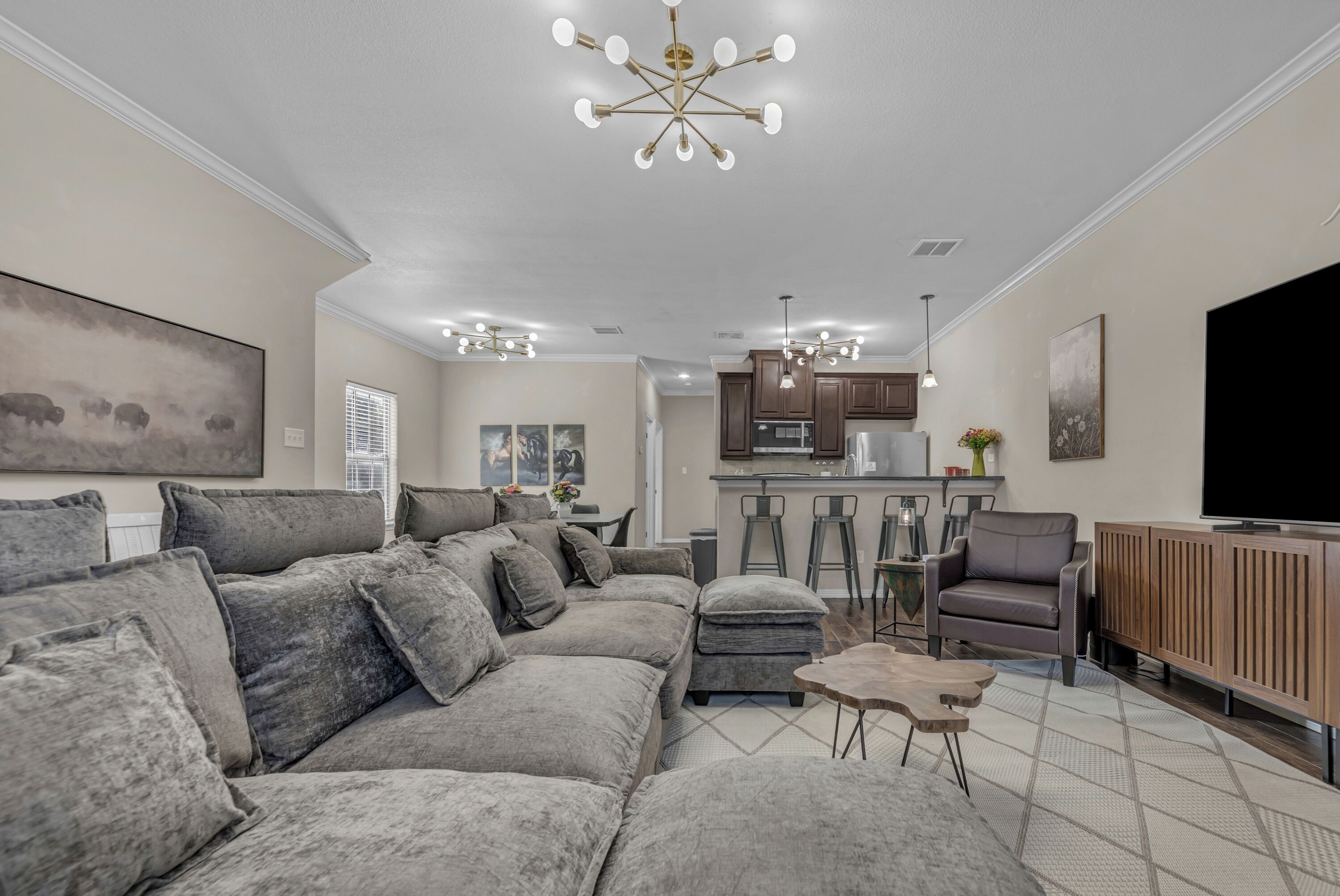 A modern living room with a sectional sofa, a coffee table, and a dining area with bar stools.