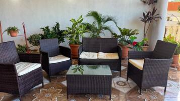 Un espace patio aménagé avec des meubles en osier, des plantes en pot et un revêtement de sol à motifs.