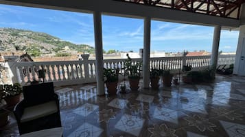 Un espace extérieur abrité, doté d’un sol carrelé, de plantes en pot et offrant une vue sur un paysage vallonné.