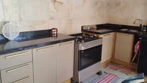 A compact kitchen with a gas stove, a built-in oven, and a sink. - Cozy little house in Chapada dos Guimarães, 5 km from the Central Square. (Chapada dos Guimarães)