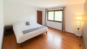A bedroom with a bed, a nightstand, a window with curtains, and a floor lamp.