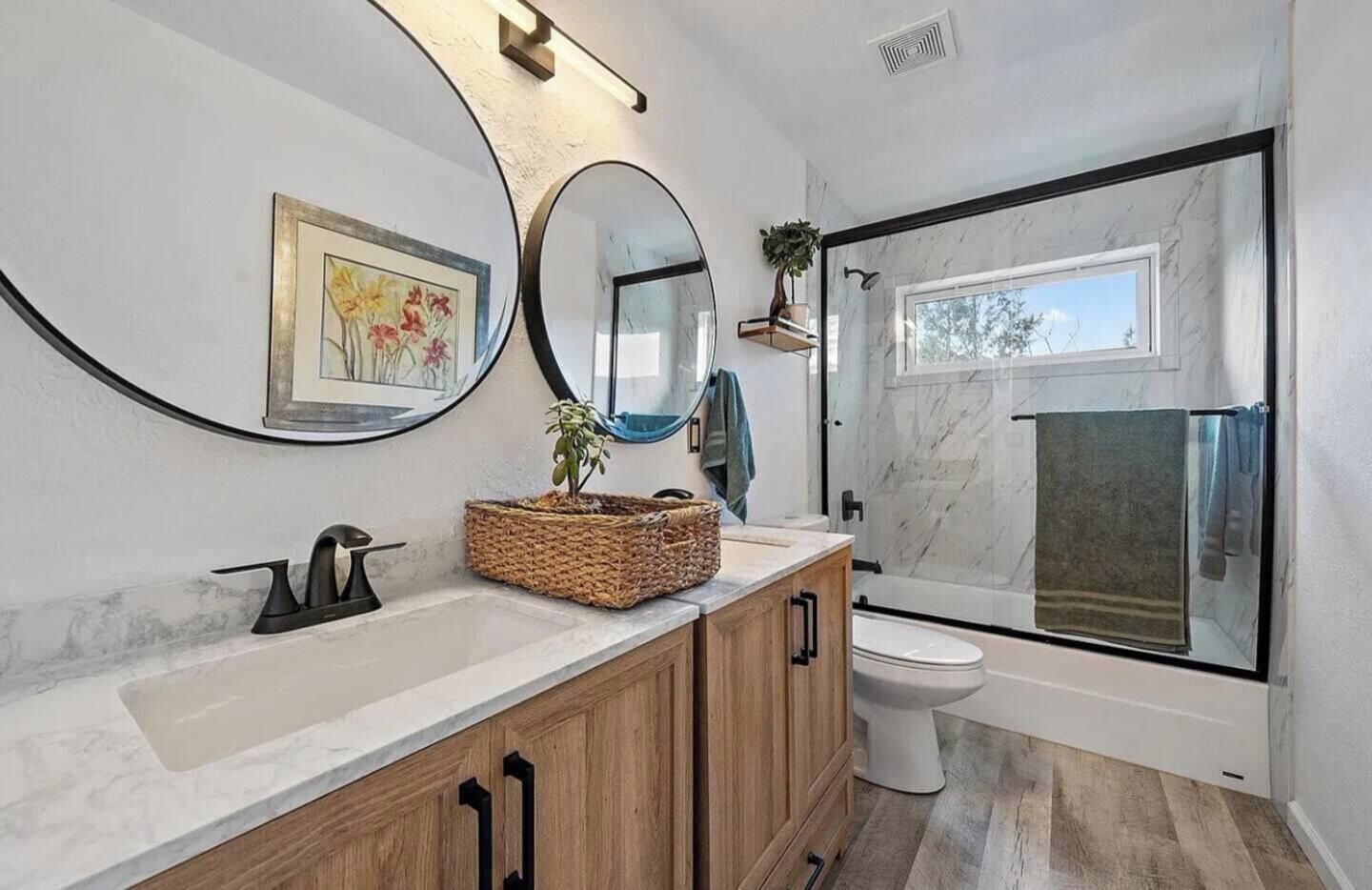 Un baño moderno con un espejo grande, un lavabo, un inodoro y una zona de ducha.