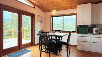 A wooden interior with a dining table, chairs, and a kitchen area with cabinets and appliances.