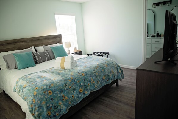 Quarto com cama, mesa de cabeceira, cômoda e espelho.