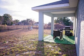 A covered patio area with a grill and seating. - Charming  brand new 3-bedroom house in Ocala with cool AC breeze (Ocala)
