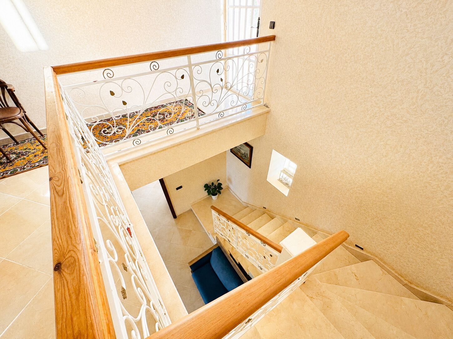 Um interior em vários níveis, com escada, piso estampado e corrimão.
