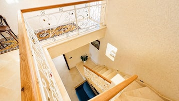 Um interior em vários níveis, com escada, piso estampado e corrimão.