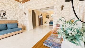 A hotel lobby with a wooden reception desk, a blue sofa, and a stone wall.
