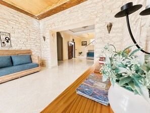 A hotel lobby with a wooden reception desk, a blue sofa, and a stone wall.