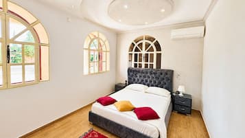 A bedroom with a large bed, two nightstands, a red rug, and a circular ceiling light.