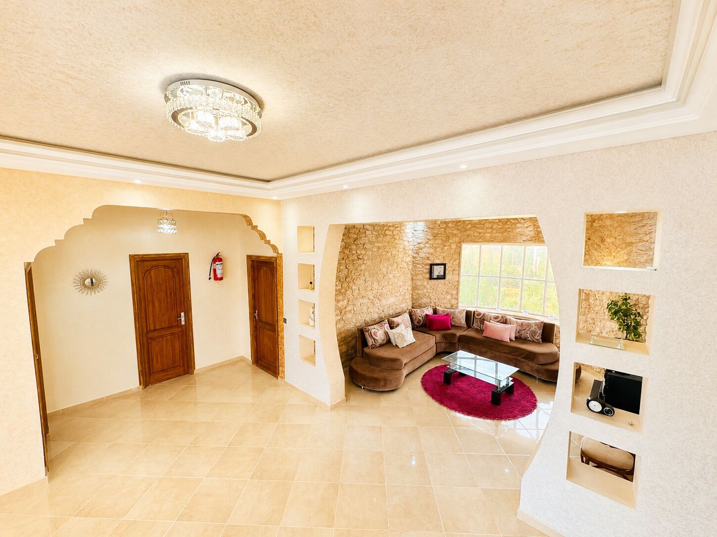 A spacious living area with a stone accent wall, a red rug, and a modern glass coffee table.