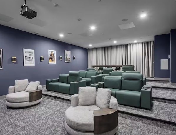 A modern cinema room with multiple seating areas, including a large curved screen and a row of green cushioned seats.