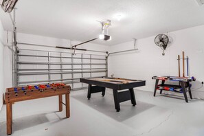 A room with a pool table, foosball table, and a fan. - 4BR Family Retreat with Private Pool (Davenport)