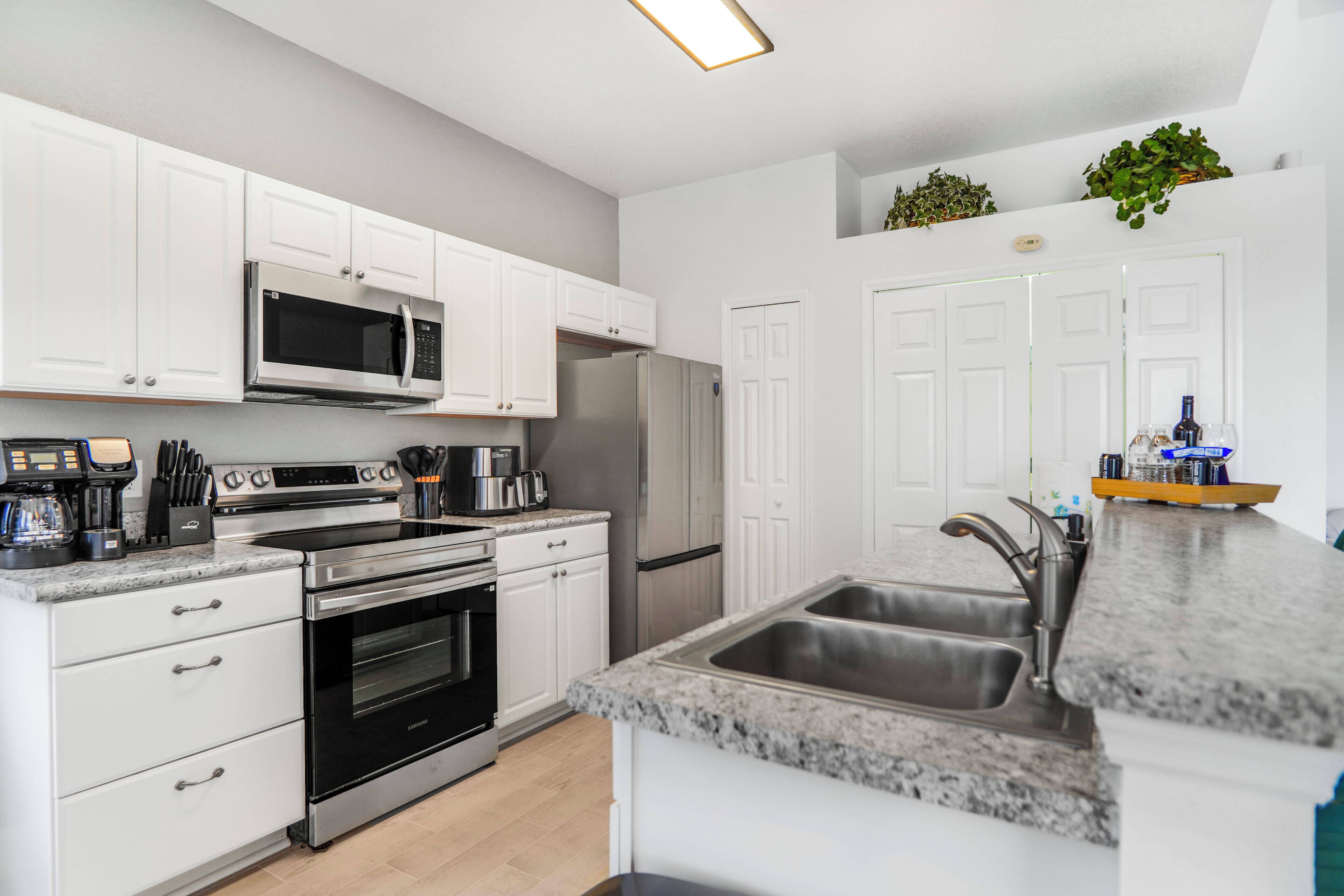 A modern kitchen with white cabinetry, stainless steel appliances, a granite countertop, and a built-in sink.
