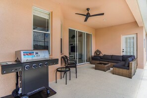 An outdoor patio with a Charbroil grill, a black sofa, and a ceiling fan. - 4BR Family Retreat with Private Pool (Davenport)