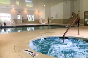 Ein Hallenbad mit Whirlpoolbereich, Liegestühlen und Blick auf das Becken.