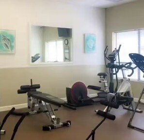 Ein Fitnessraum mit Trainingsgeräten, einem Spiegel und Kunstwerken an den Wänden.