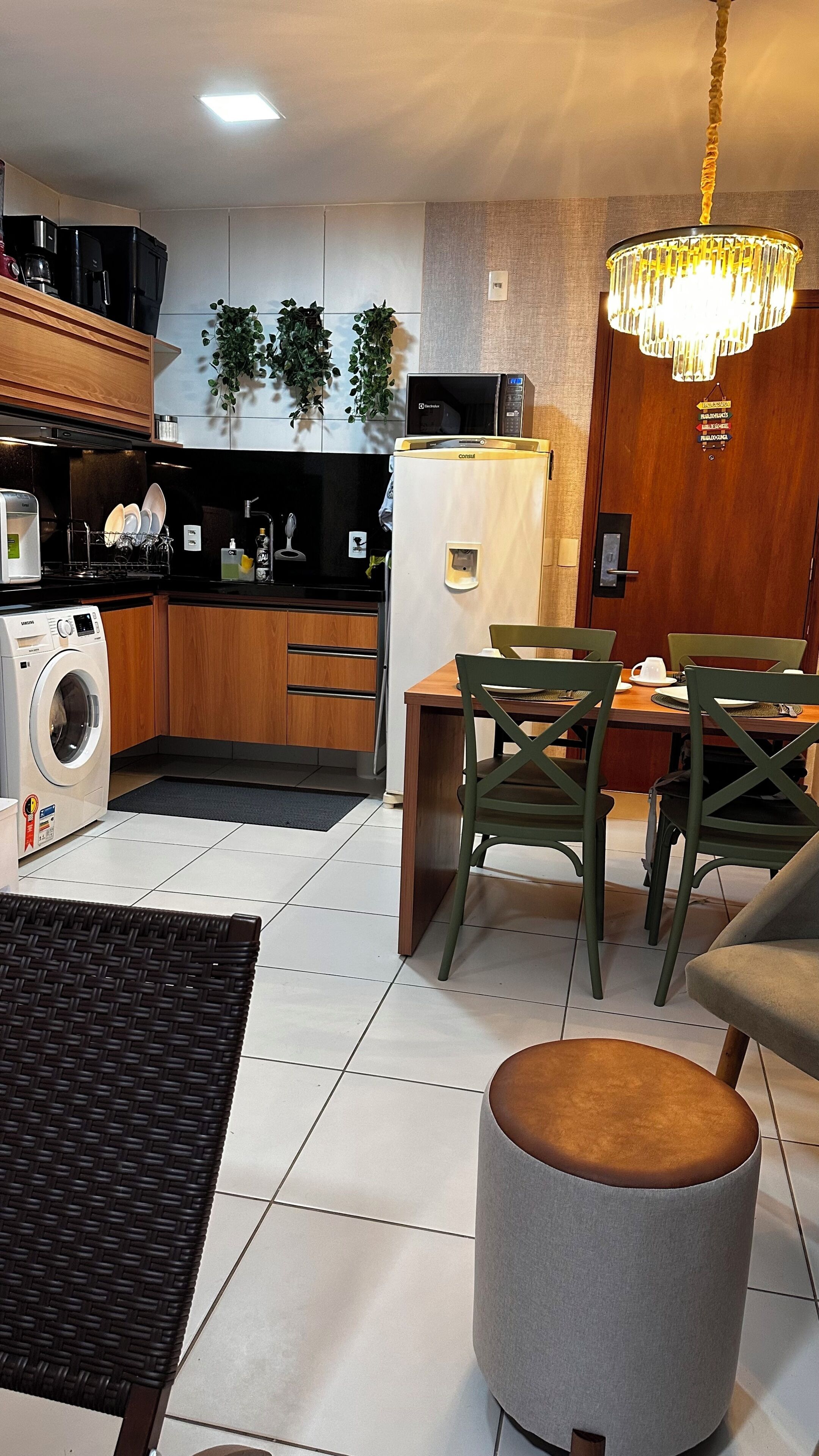 A modern kitchen with a washing machine, a microwave, and a refrigerator. There is a dining area with a table and chairs.