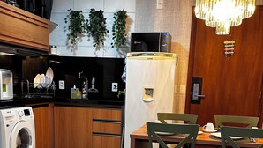 Cocina moderna con lavadora, microondas y refrigerador. Cuenta con un comedor con mesa y sillas.