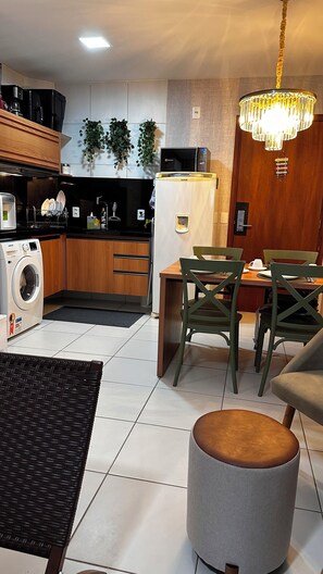 Cuina moderna amb rentadora, microones i neverà. Zona menjador amb taula i cadires.