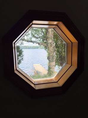 A hexagonal window with a view of a lake and dock. - Serene 3-bedroom house in charming Newark perfect for relaxing stays (Newark)
