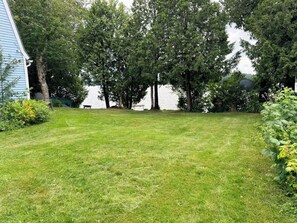 A grassy yard with a bench and trees, a satellite dish, and a house with blue siding. - Serene 3-bedroom house in charming Newark perfect for relaxing stays (Newark)