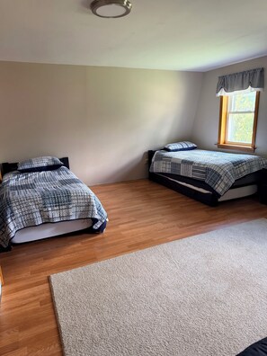 A room with two beds, a window with curtains, a wooden floor, and a carpet. - Serene 3-bedroom house in charming Newark perfect for relaxing stays (Newark)