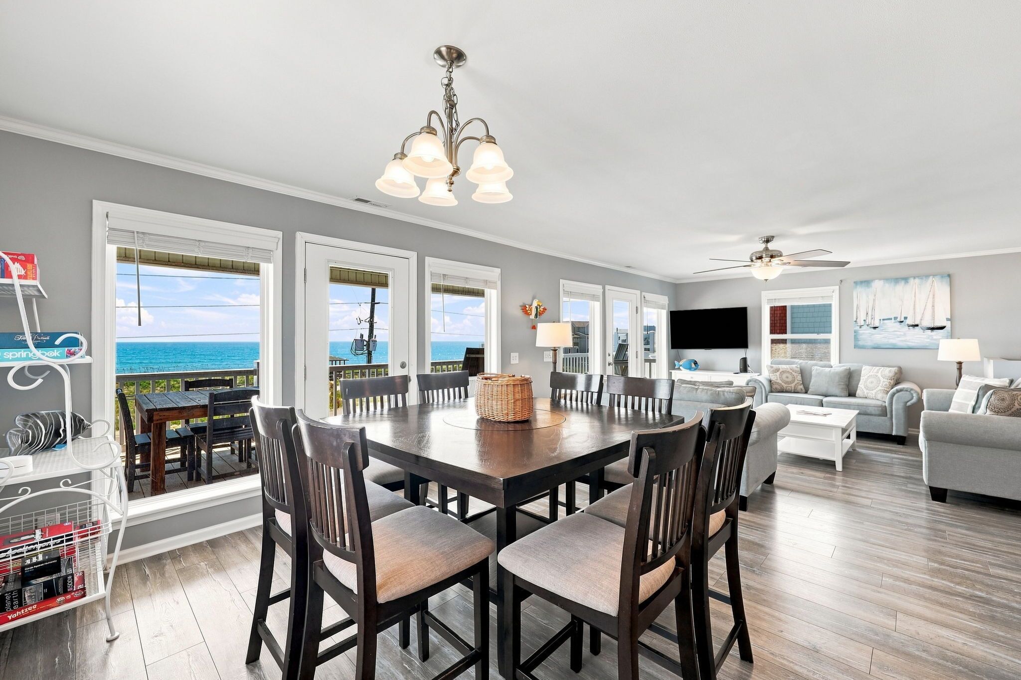 A spacious living room with a dining area, large windows, and a view of the ocean.