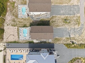 Vista aérea de un hotel con dos piscinas, un espacio al aire libre cubierto y un estacionamiento.