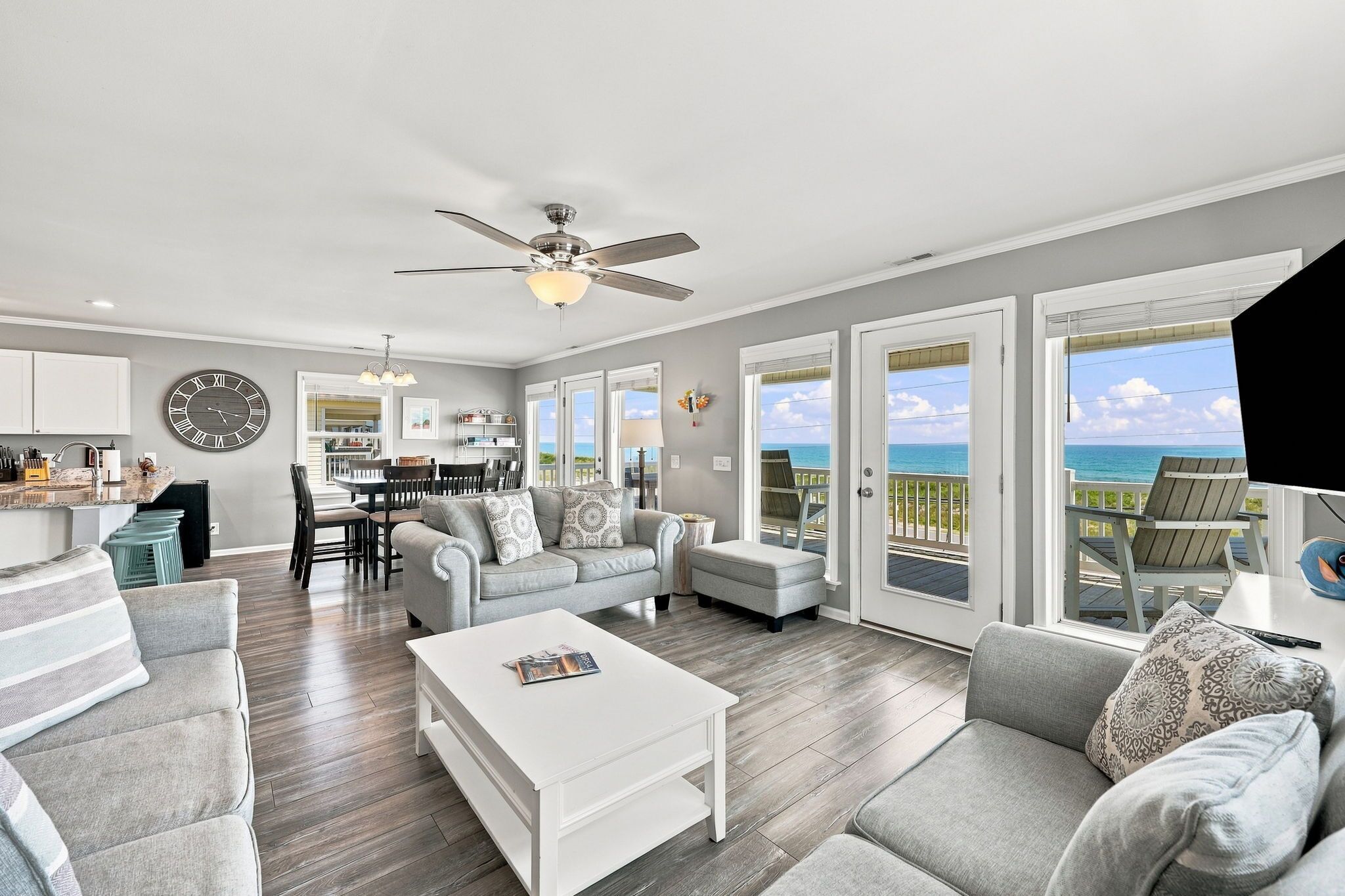 A spacious living room with a large window, a dining area, and a kitchen.