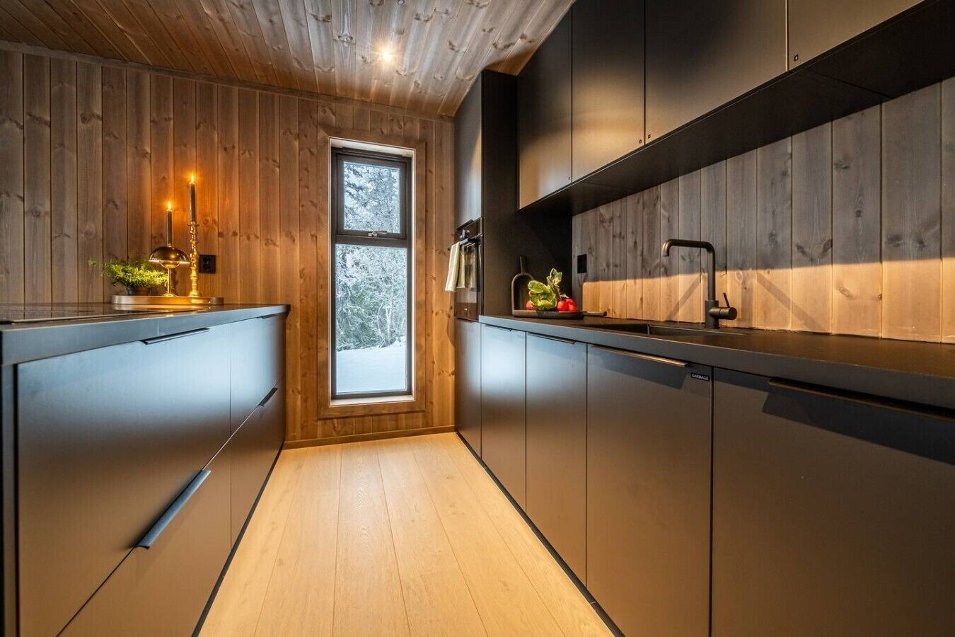 A modern kitchen with wooden walls, a window, and a sink.