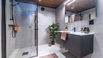 A modern bathroom with a glass shower enclosure, a sink with a towel, and a potted plant.